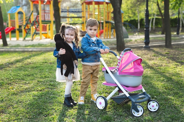 Little boy and little girl baby walk with a stroller for dolls.