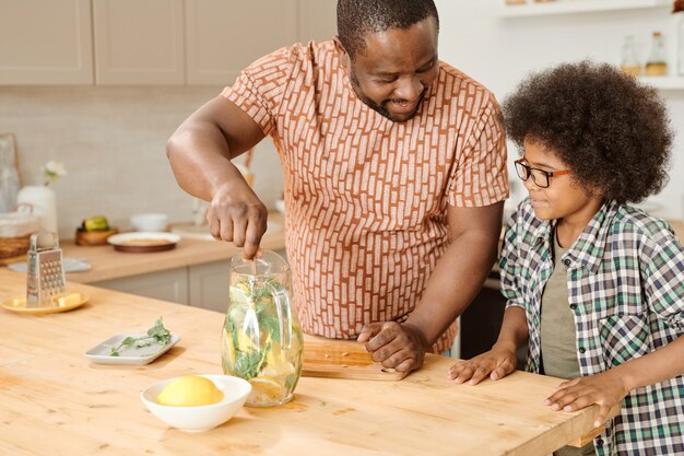 Little boy looking at his father mixing lemonade in jug