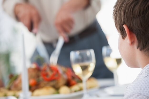 ローストチキンを彫る男を見ている小さな男の子