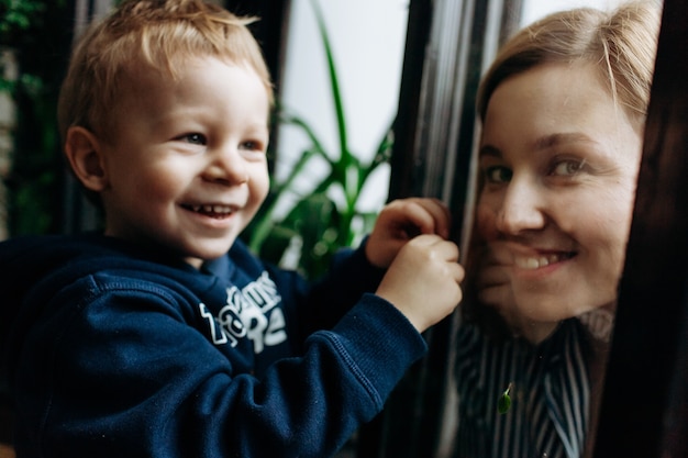 little boy looks curious playing with greenery and his mom
