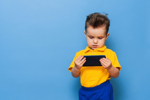 A little boy looks at the screen of a mobile phone.