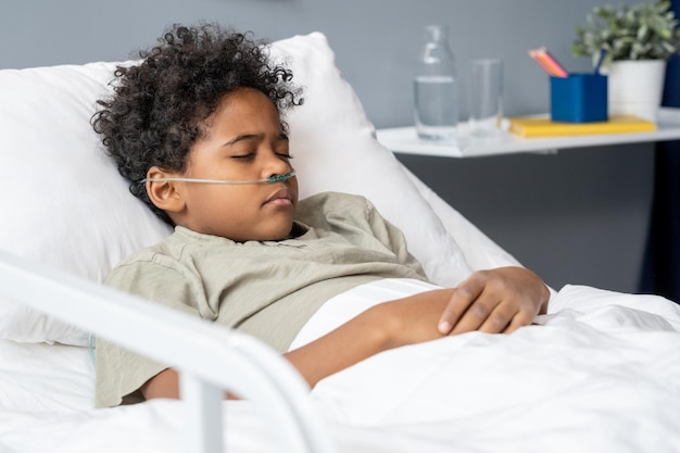 Little boy lying in bed with inhaling equipment