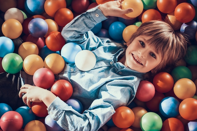 Little Boy Lying in Pool full of Colorful Balls