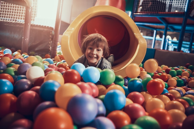 Little Boy Lying in Pool full of Colorful Balls