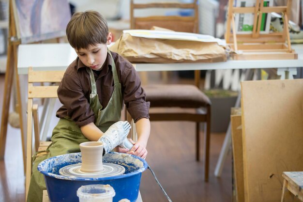 A little boy makes a clay product at a potter's wheel