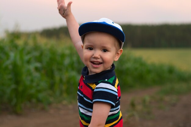 A little boy makes faces and plays in a cornfield