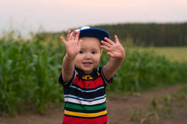 A little boy makes faces and plays in a cornfield