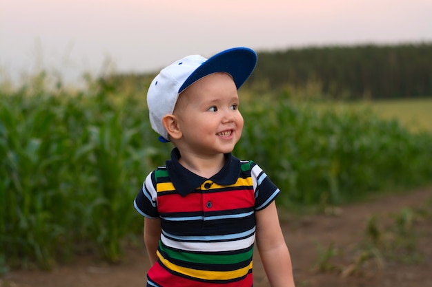 A little boy makes faces and plays in a cornfield