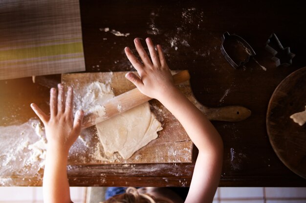 little boy making cookies from dough in kitchen
