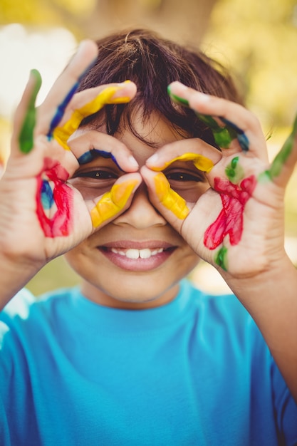 Little boy making glasses with his painted hands