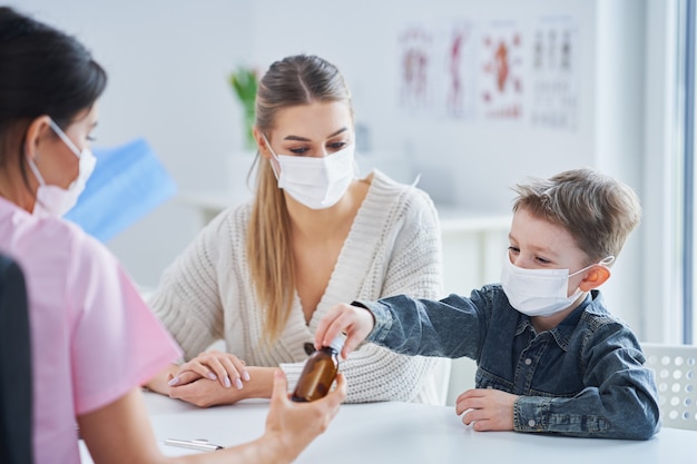 little boy in mask having medical examination by pediatrician during pandemic