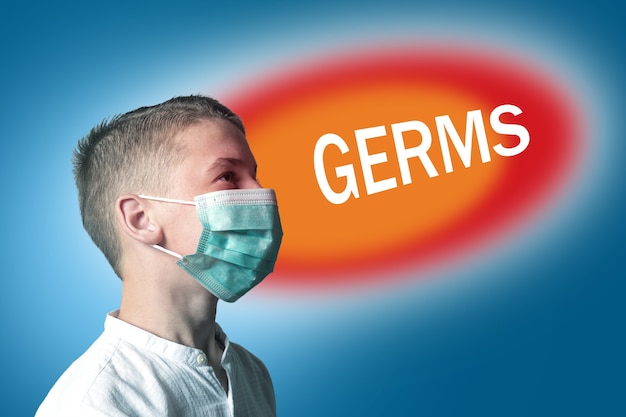 Little boy in a medical mask on a bright background with inscription GERMS