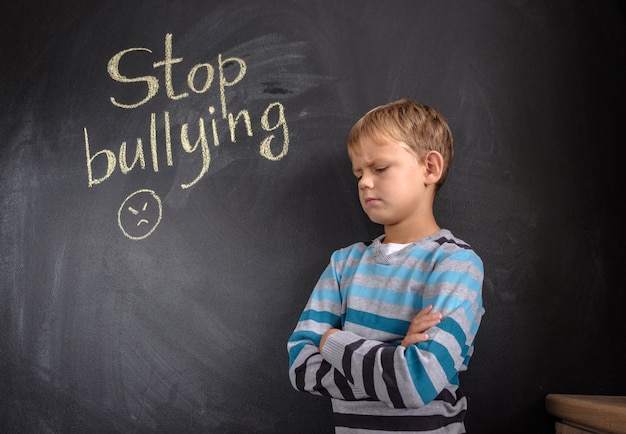 Little boy near chalkboard with words