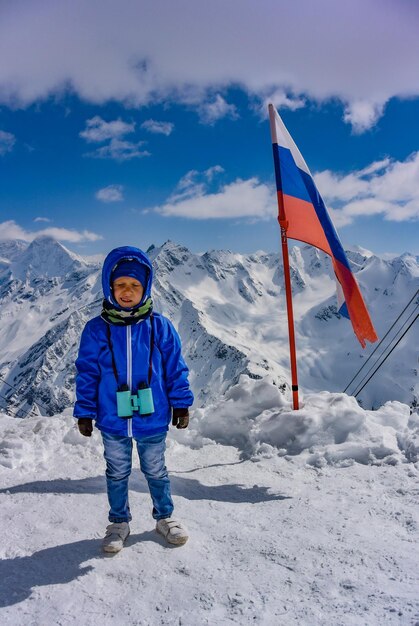 사진 눈 덮인 산의 배경에 어린 소년과 러시아 elbrus 러시아의 국기 2019년 4월 25일