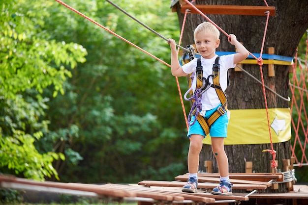 Little boy overcomes the obstacle in the rope park.