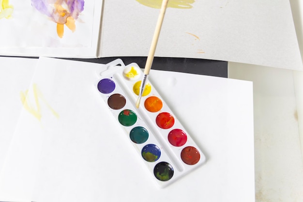 A little boy paints with watercolor paints on a table