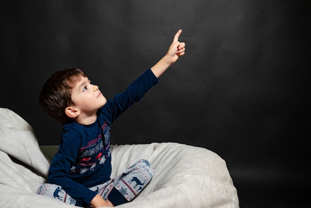 Little boy in pajamas on a black background shows up