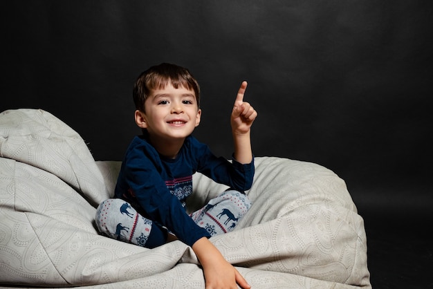 Little boy in pajamas on a black background shows up