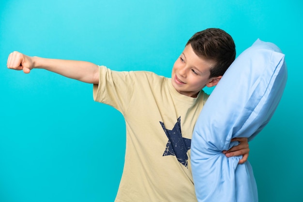 Маленький мальчик в пижаме на синем фоне показывает большой палец вверх