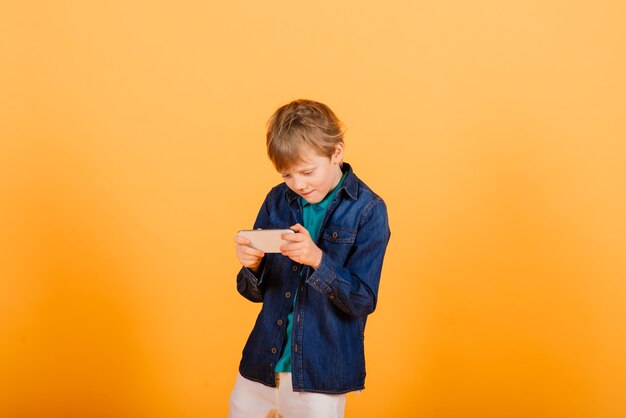 The little boy phones on the yellow wall