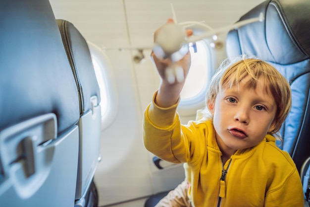 Little boy play with toy plane in the commercial jet airplane flying on vacation