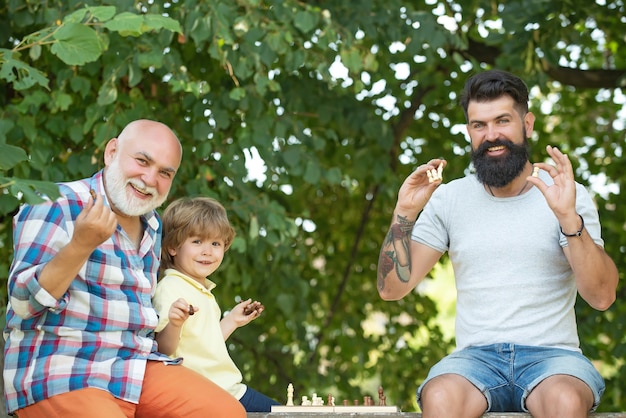 Little boy playing chess with his Grandfather and Father