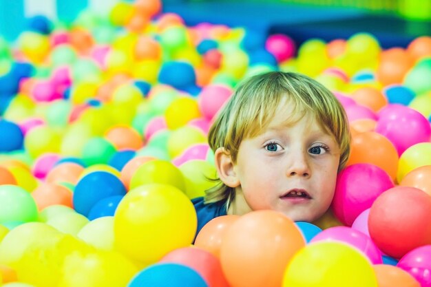 カラフルなプラスチックボールプールで遊ぶ少年