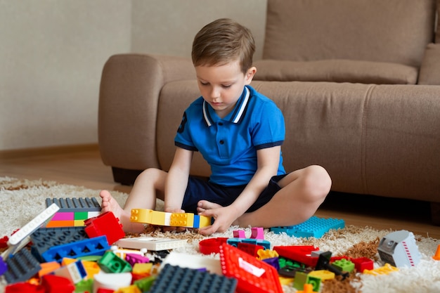 Ragazzino che gioca kit di costruzione sul pavimento