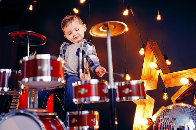 Маленький мальчик играет на барабанах на сцене
