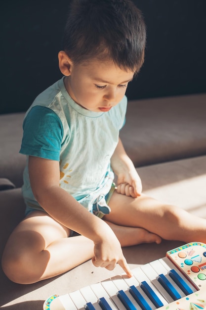 Little boy playing electrical toy piano on floor early development for toddler and baby