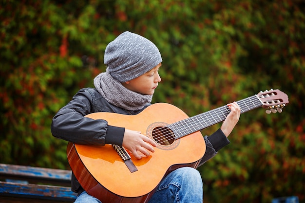 Little boy playing guitar on nature