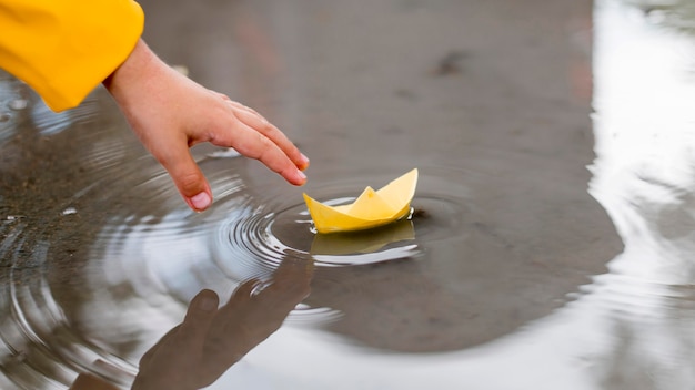 写真 紙のボートのクローズアップと水で遊ぶ少年