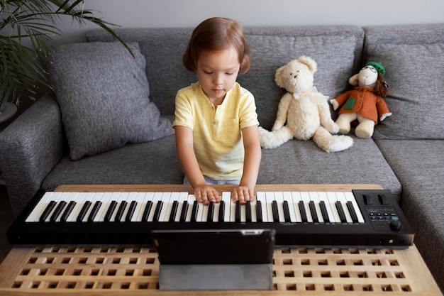 Photo little boy playing keyboard at home