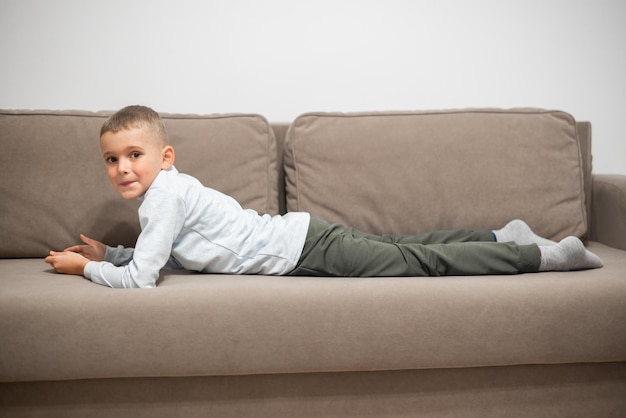 Little boy playing mobile game on smartphone sitting on a sofa top view Child leisure at home video