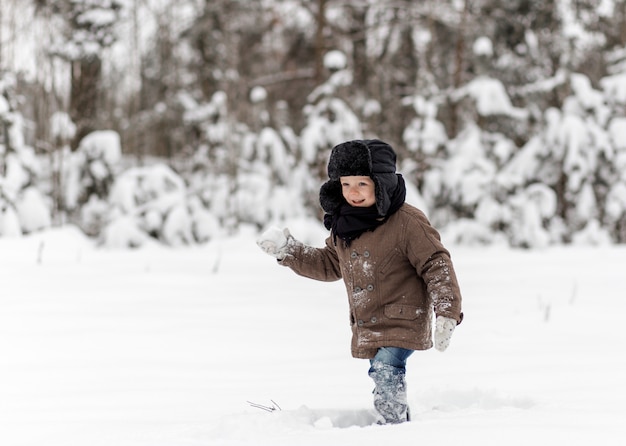 冬の自然の中で雪玉を遊ぶ少年