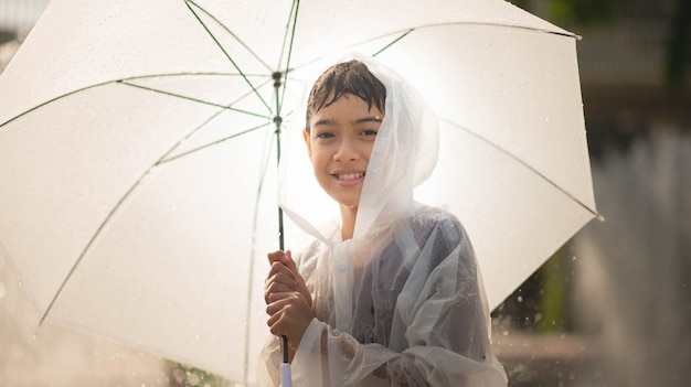 Little boy playing water drops fountain under the cloth and umbrella