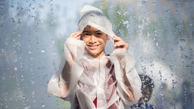 Foto il ragazzino che gioca l'acqua cade la fontana sotto il panno e l'ombrello