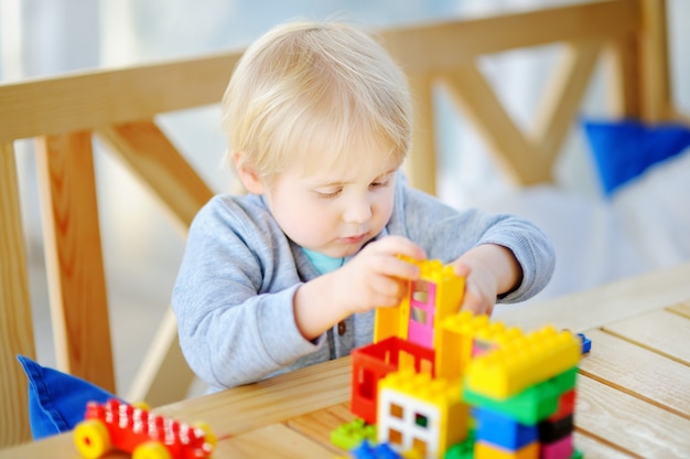 Little boy playing with colorful plastic blocks at kindergarten or at home