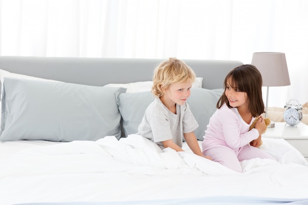 Little boy playing with his sister on their parents' bed