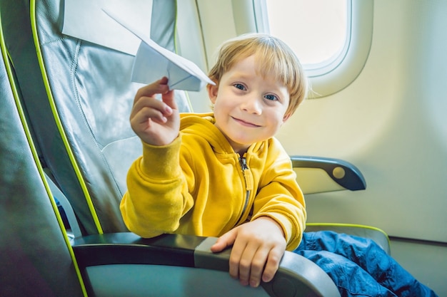 Little boy playing with paper plane in the airplane