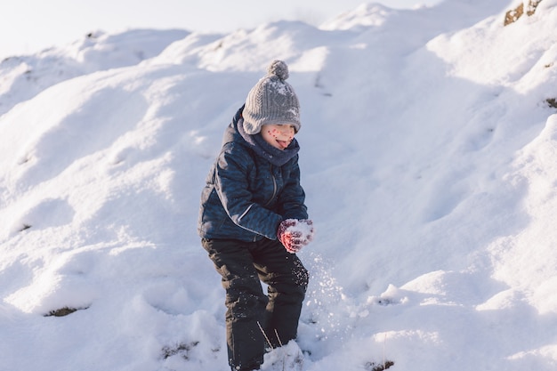 Маленький мальчик играет со снегом