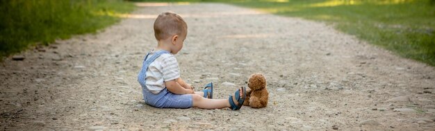 写真 歩道でテディベアと遊ぶ小さな男の子