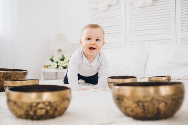 Little boy playing with Tibetan singing bowls sitting on the bed