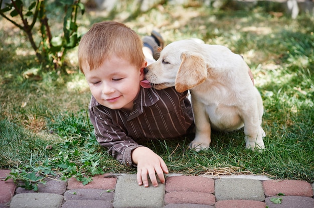 Ragazzino che gioca con un cucciolo di labrador bianco