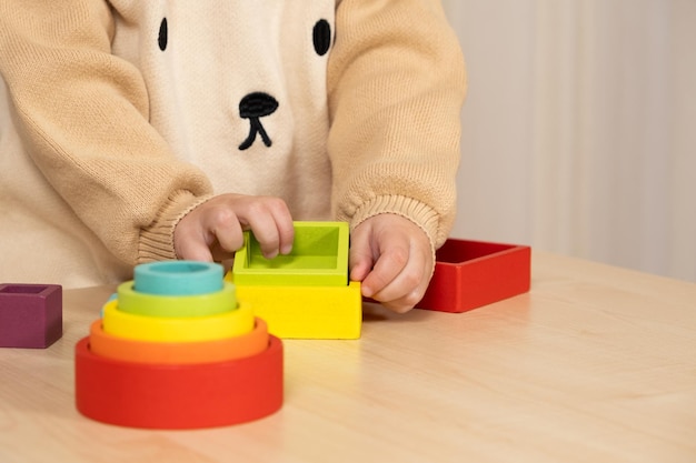 Little boy playing with wooden multicolored Montessori toys Hands closeup