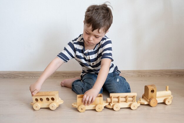 木製の電車で遊んでいる少年。エコおもちゃ。