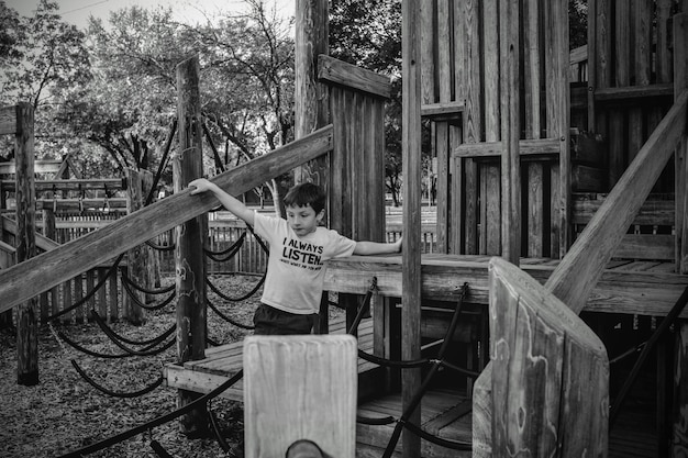 Photo little boy playing on wooden jungle gym at park