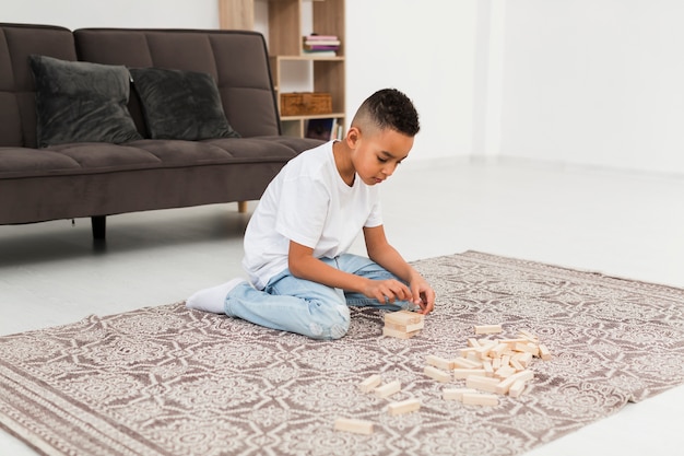 Little boy playing a wooden tower game at home