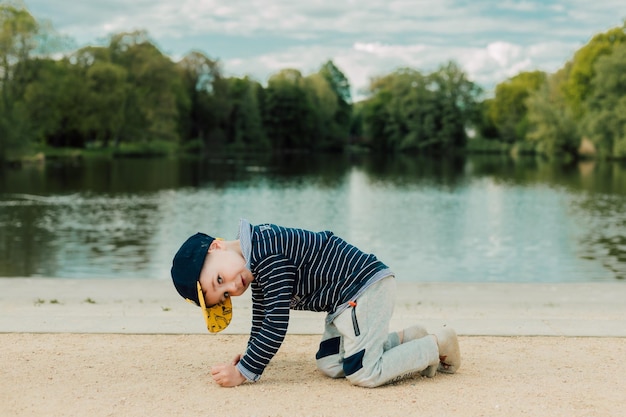 A little boy plays by the river on a sunny day