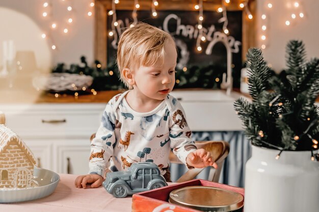 Little boy plays in the kitchen with New Year's decor. The pastime of children in quarantine